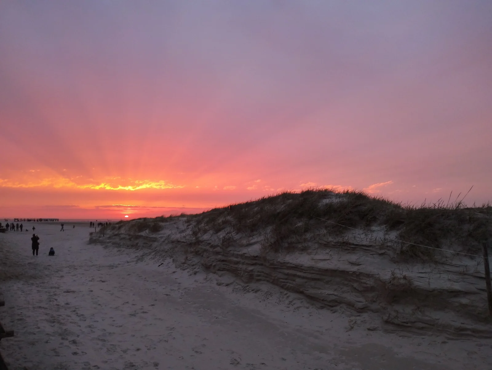 Orange-roter Sonnenuntergang hinter den Dünen am Strand von St. Peter-Ording